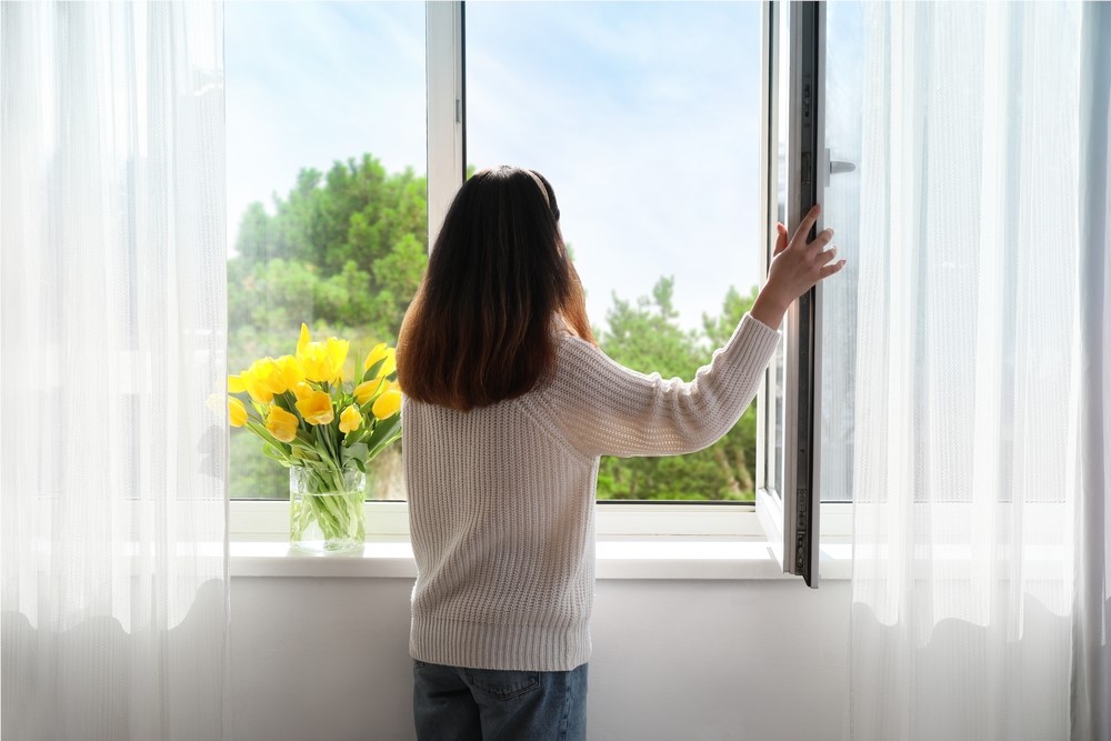 Woman looks out of window onto field