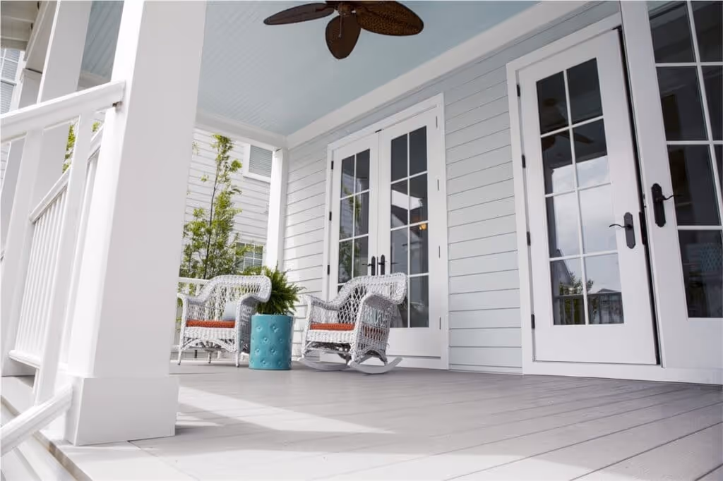 Serene home exterior featuring pristine white siding by HXHome Solutions, complemented by a new deck adorned with inviting outdoor chairs for a perfect blend of style and comfort.