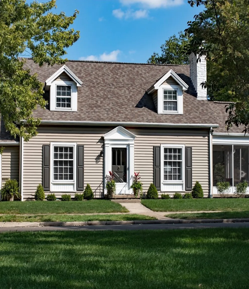 Two-story house with beige vinyl siding, black shutters and white double-hung windows